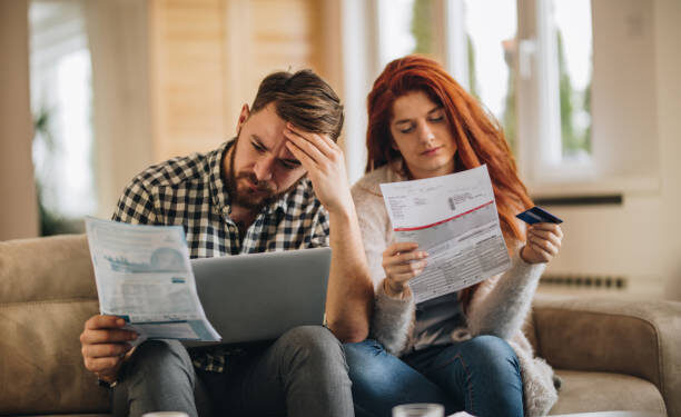 Worried couple feeling frustrated while have to pay their bills over Internet.