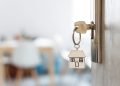 Key with keychain in a house shape in the door keyhole. Buy new home concept. Real estate market.