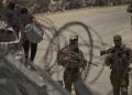 Israeli soldiers stand guard as Syrian Druze people cross back into Syria at the Israeli-Syrian border, in the Israeli-controlled Golan Heights town of Majdal Shams, Thursday, July 17, 2025. (AP Photo/Leo Correa)