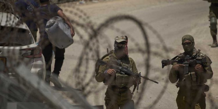 Israeli soldiers stand guard as Syrian Druze people cross back into Syria at the Israeli-Syrian border, in the Israeli-controlled Golan Heights town of Majdal Shams, Thursday, July 17, 2025. (AP Photo/Leo Correa)