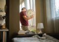 Mature man over 50s arranging his wall clock, changing the batteries at home. The single lifestyle concept.