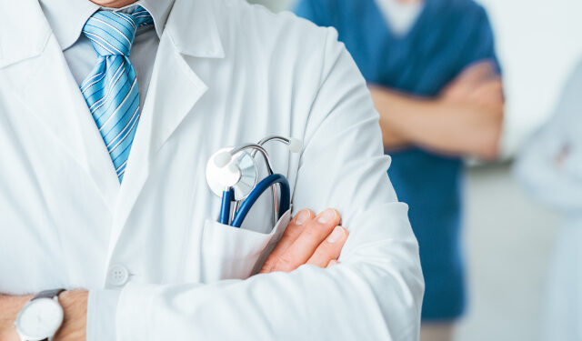 Professional medical team posing, doctor's lab coat and stethoscope close up, selective focus